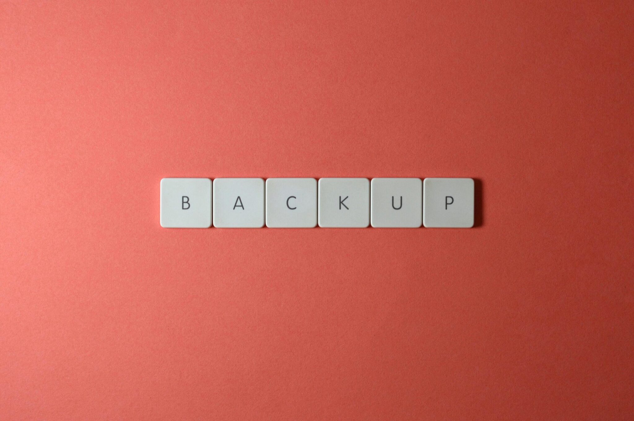 Simple-Backup-and-Recovery-Plans-Every-Small-Business-Needs-scaledjpg | ALCON DTS: Austin, TX Best Managed IT Support Services Free Close-up of keyboard keys spelling 'BACKUP' placed on a coral-colored surface. Stock Photo